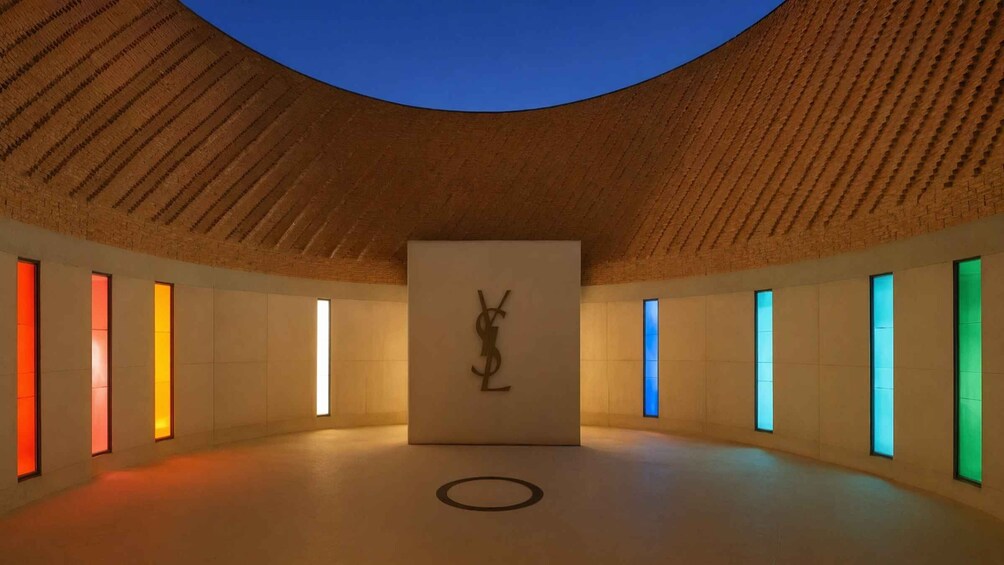 A modern interior with a wooden ceiling, a central sculpture, and colorful illuminated windows. 1