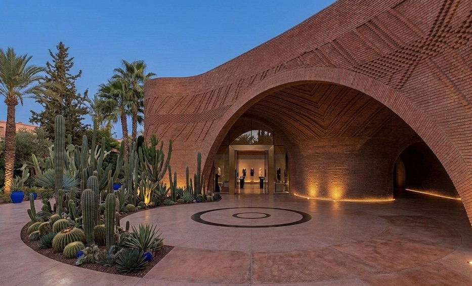 A modern building with a curved brick facade and a circular design on the ground. 2