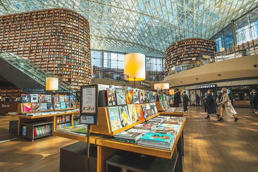 A modern library interior with bookshelves, tables with books, and a Starbucks. 5
