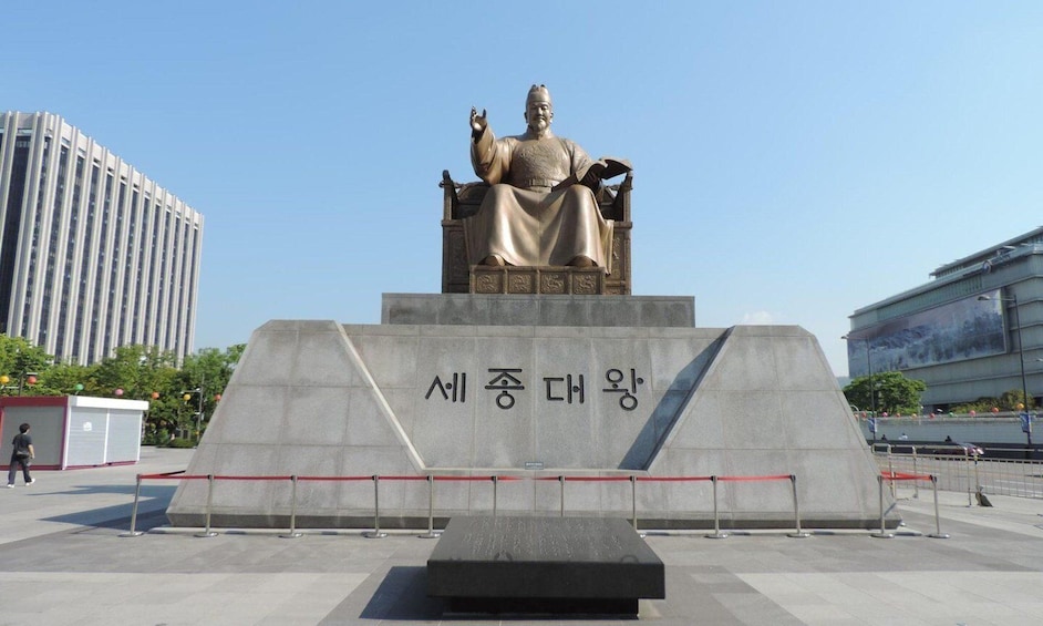 A statue of a seated figure on a pedestal with Korean text. 5