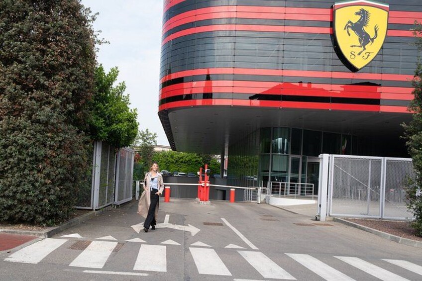 A modern building with a Ferrari logo, a pedestrian crossing, and a person walking. 2