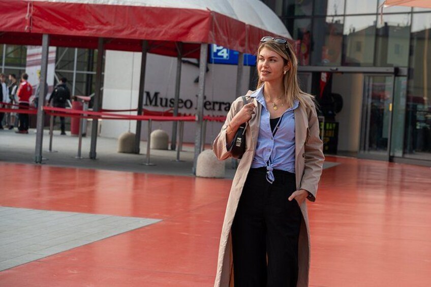 A person standing in front of a museum with a red canopy, holding a bag. 1