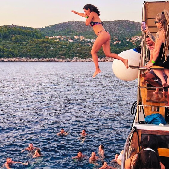 A woman jumping into the water from a boat, with several people swimming below. 1