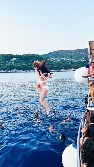 A person jumping into the water from a boat, with a mountainous landscape in the background. 2