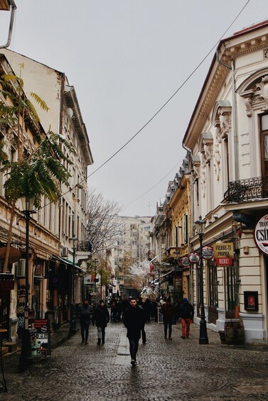 A cobblestone street lined with historic buildings, pedestrians, and street signs. 2