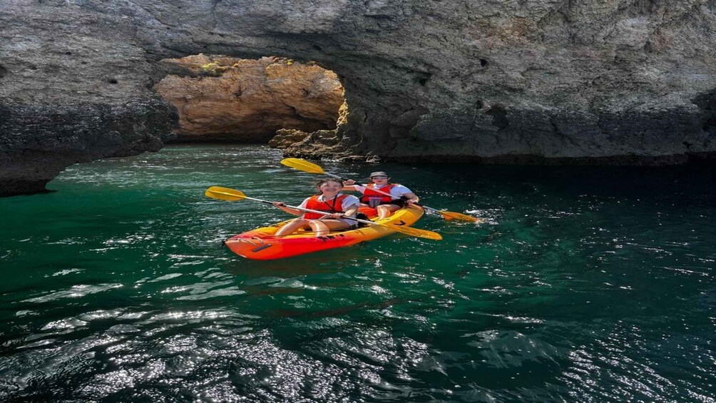 A group kayaking through a narrow water passage with rocky walls. 2