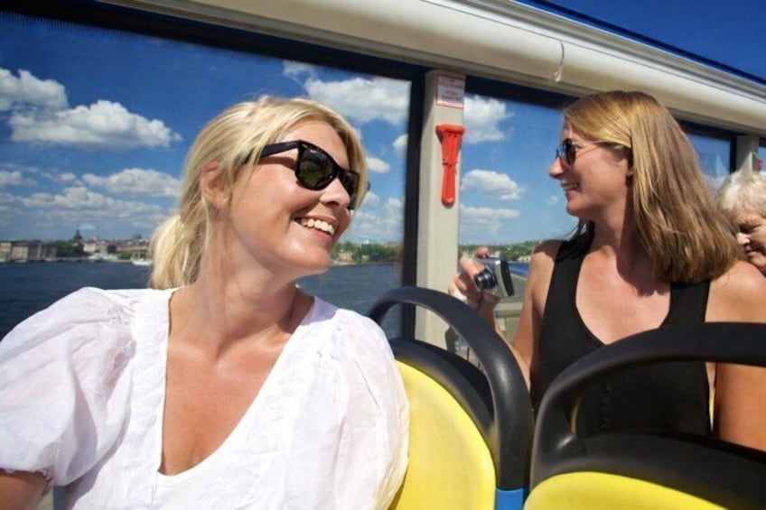 Two people on a boat with a river and buildings in the background. 2