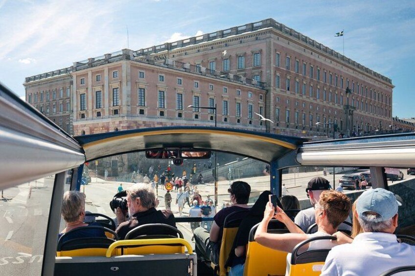En grupp människor i en gul buss, en stor byggnad med klassisk arkitektur och en klar himmel. 2