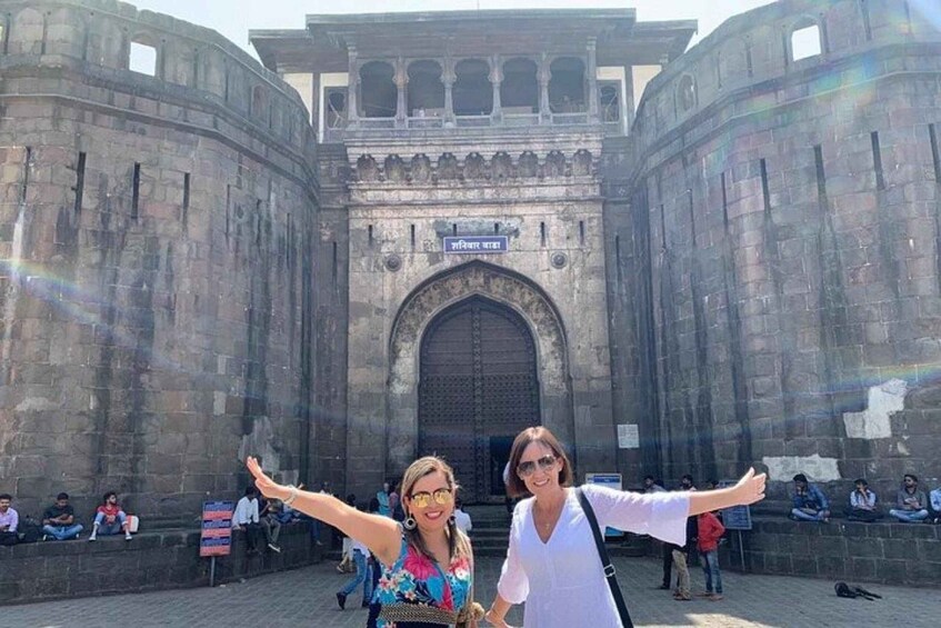 A historic stone gate with two people posing in front. 5