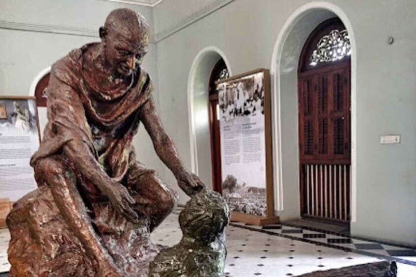 A bronze statue of a seated man with a child in a room with arched doorways and a checkered floor. 3