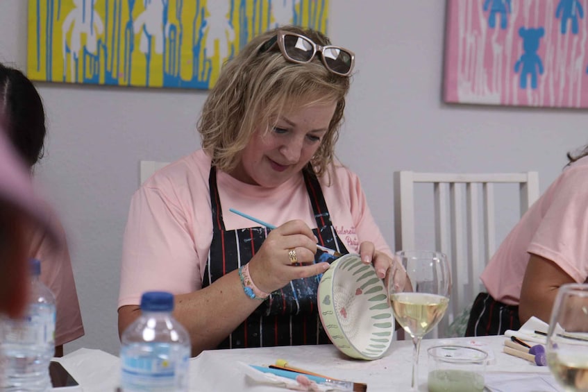 A person painting a ceramic plate with a brush. 2