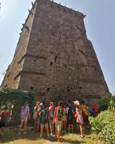 A group of people standing in front of a large, ancient stone tower. 5
