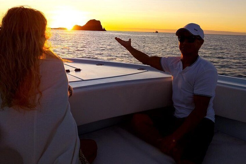 A boat at sunset with a person gesturing and another person facing away. 3