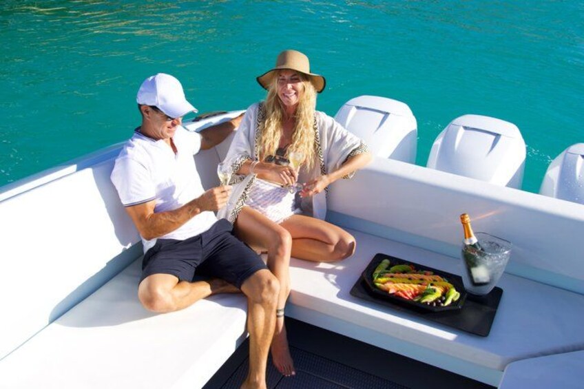 Two people on a boat with a drink and a plate of food. 2