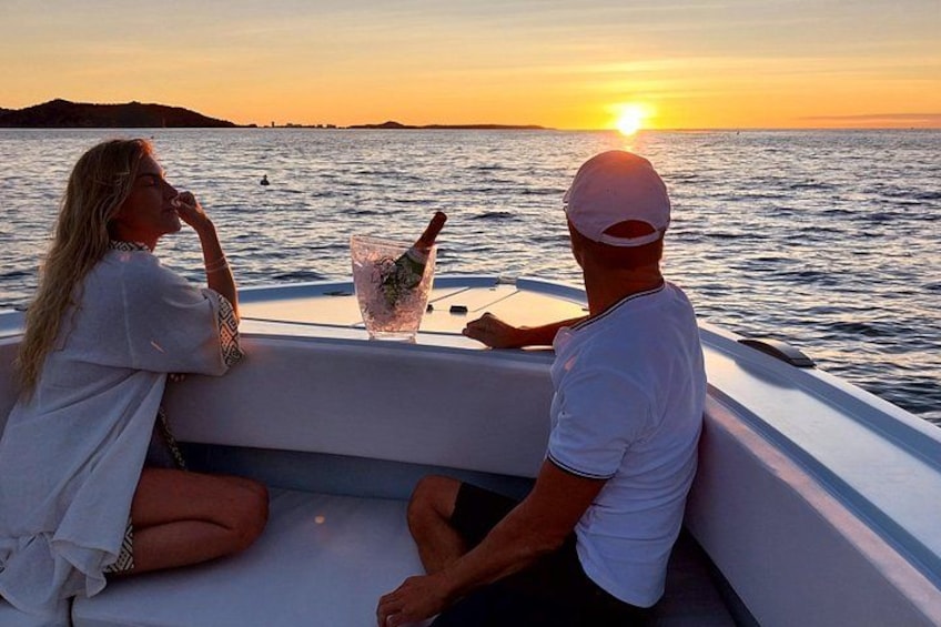 A boat with two people, a sunset, and a calm sea. 2