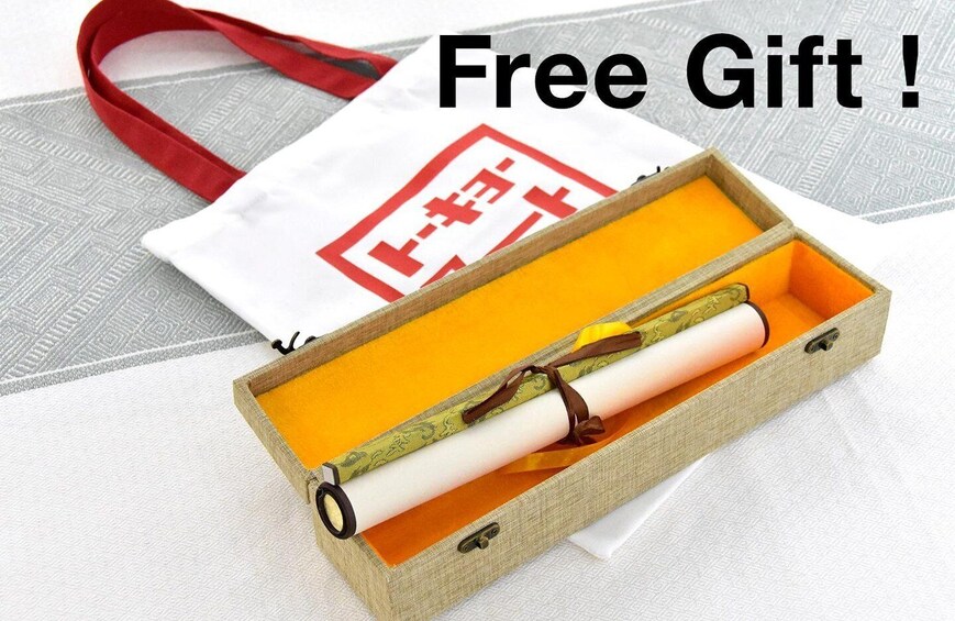 A gift box with a rolled-up item, a red strap, and a white bag with red text. 4