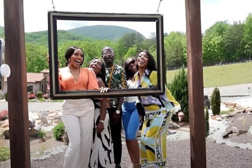 A group of people posing with a framed picture in a garden with a mountain in the background. 1