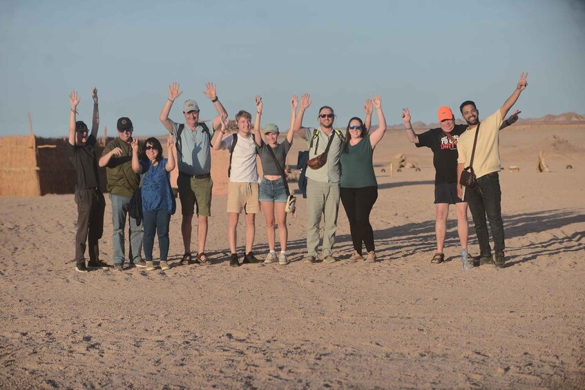 A group of people standing in a desert with their hands raised. 2