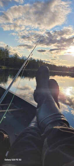A person fishing with a rod on a boat, calm water, and a sunset sky. 3