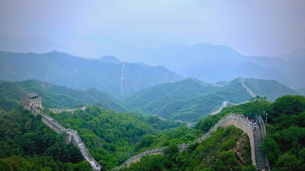 The Great Wall of China winding through lush green mountains. 2