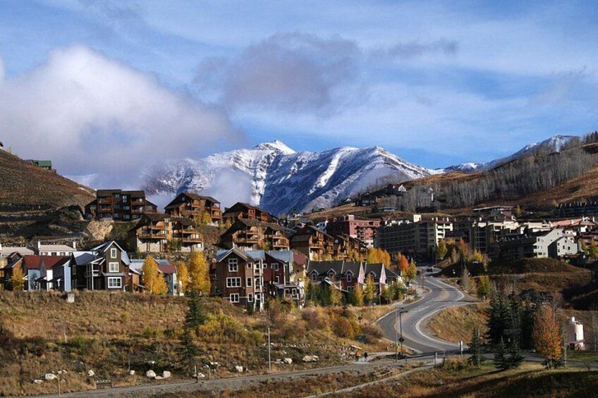 A town with buildings, a winding road, and snow-capped mountains in the background. 2