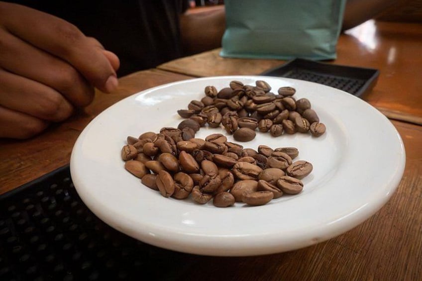 A white plate with coffee beans on a wooden table. 2