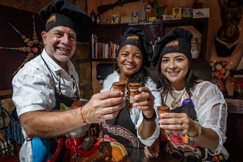 Three people toasting with drinks in a rustic setting with shelves and decorative items in the background. 1
