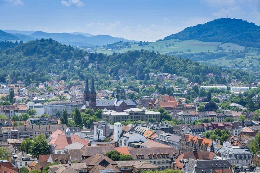 A town with historic buildings, a prominent church, and rolling hills in the background. 2