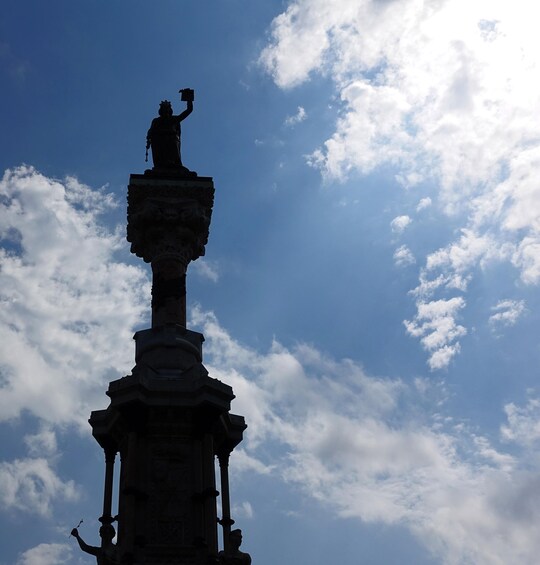 A silhouette of a statue against a partly cloudy sky. 3