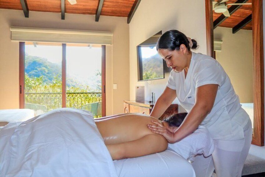A person receiving a massage on a bed in a room with a balcony. 2