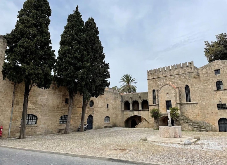 A historic stone building with arched doorways and a castle-like structure. 2