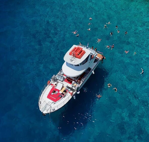 A boat with people swimming in the water around it. 1