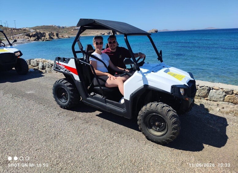 A golf cart parked by a rocky shoreline with a clear blue sea in the background. 5