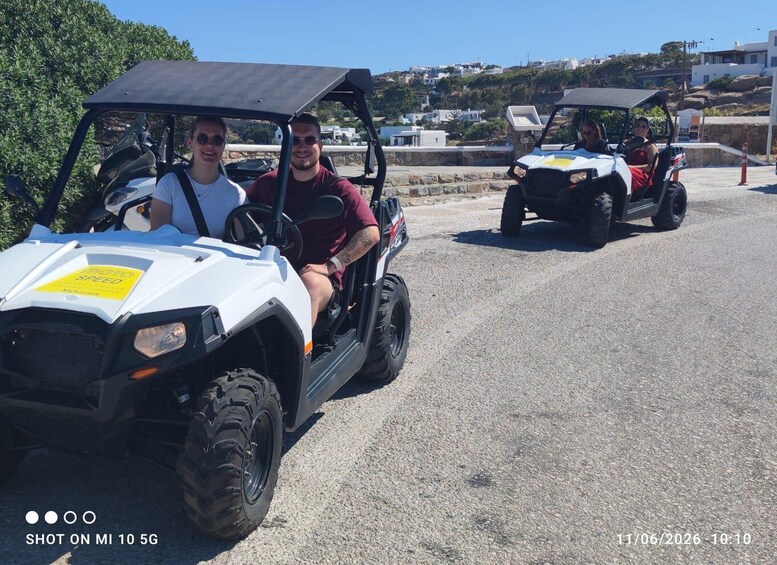 Two golf carts on a paved road with a hilly landscape in the background. 2