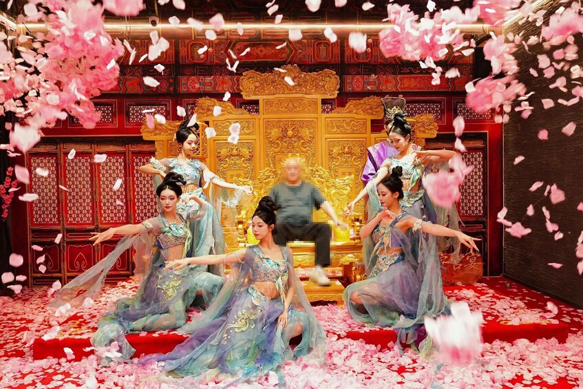 A traditional performance with dancers in blue and purple costumes, a golden throne, and red patterned walls. 5