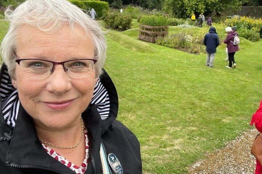 A person in a black jacket with striped collars, a necklace, and a lanyard with a badge. 4
