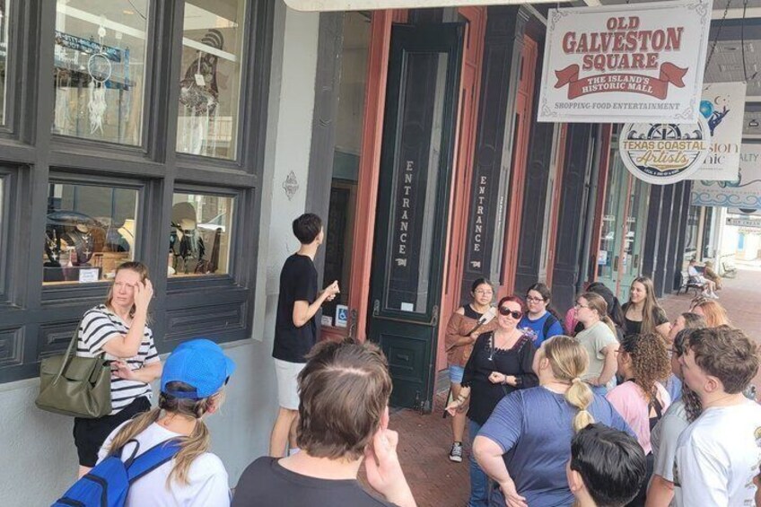 A group of people outside a building with a sign reading 'Old Galveston Square.' 5