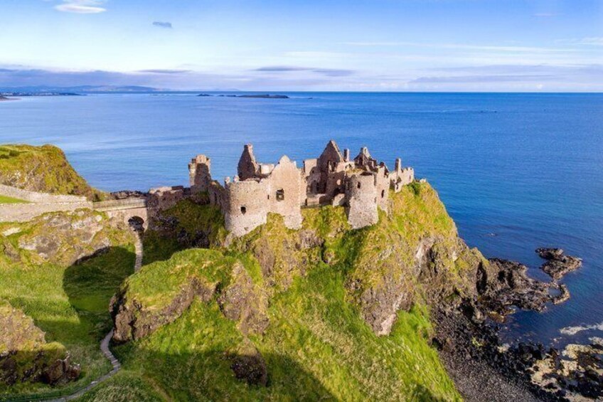 A coastal castle on a grassy cliff overlooking the sea. 3