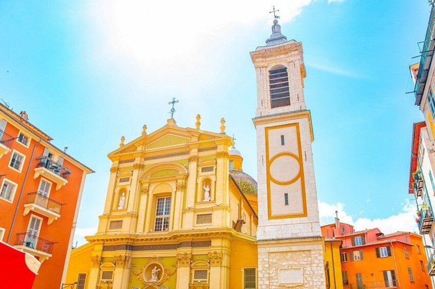 A yellow church with a bell tower and adjacent orange buildings. 2