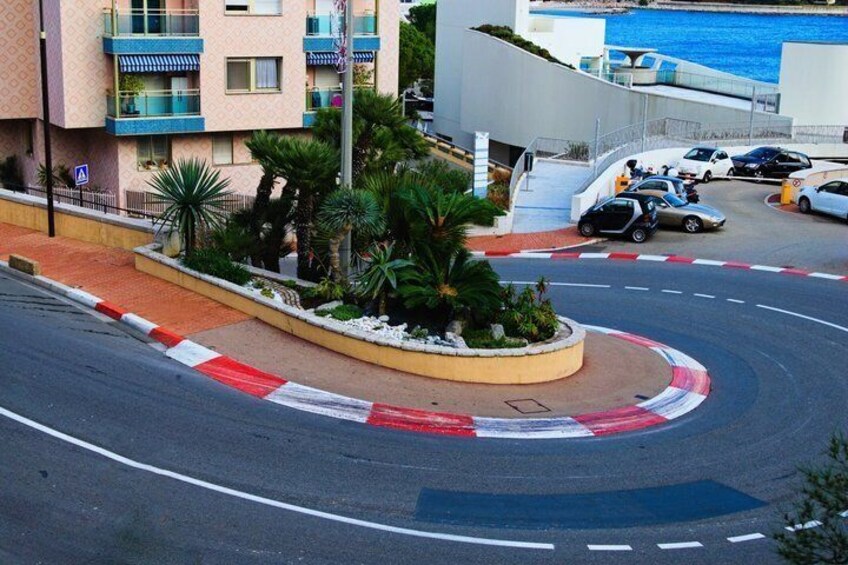A roundabout with palm trees, a parking lot, and buildings with balconies. 4