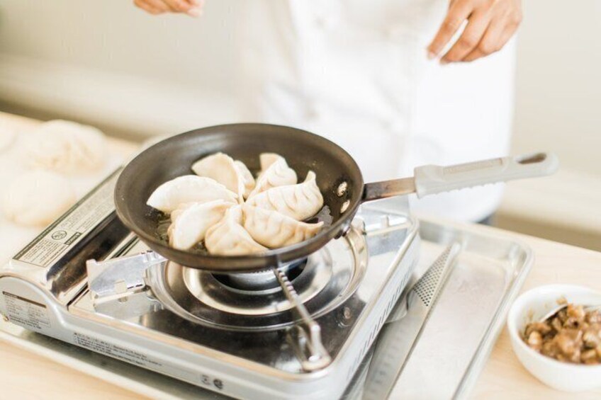 A person cooking dumplings on a portable stove. 5