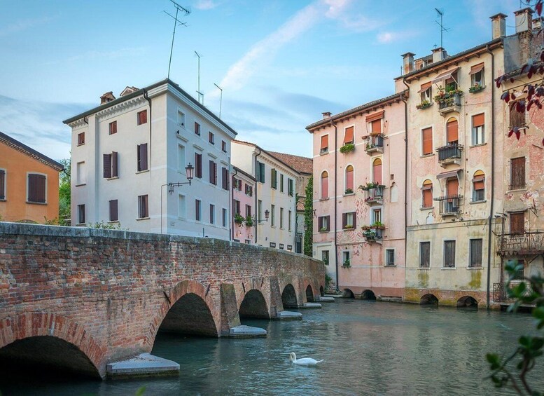 A canal with a brick bridge and colorful buildings on either side. 2