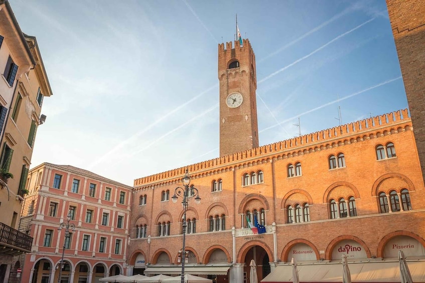 A historic building with a clock tower, arched windows, and a sign for 'daPino Pizzeria.' 1