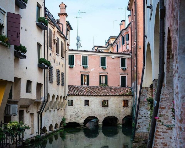 A narrow canal flanked by historic buildings with arched windows and balconies. 5