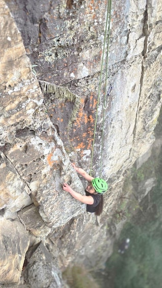 A person rock climbing on a cliff with a helmet and harness. 3