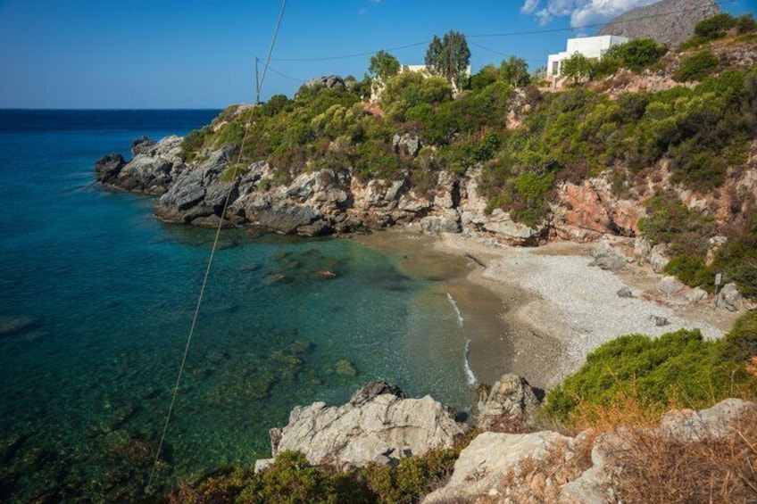 A coastal landscape with clear waters, rocky terrain, and vegetation. 3