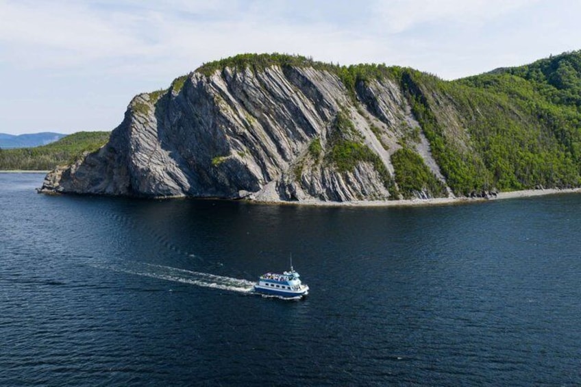 A boat on a calm lake with a large rocky island in the background. 3
