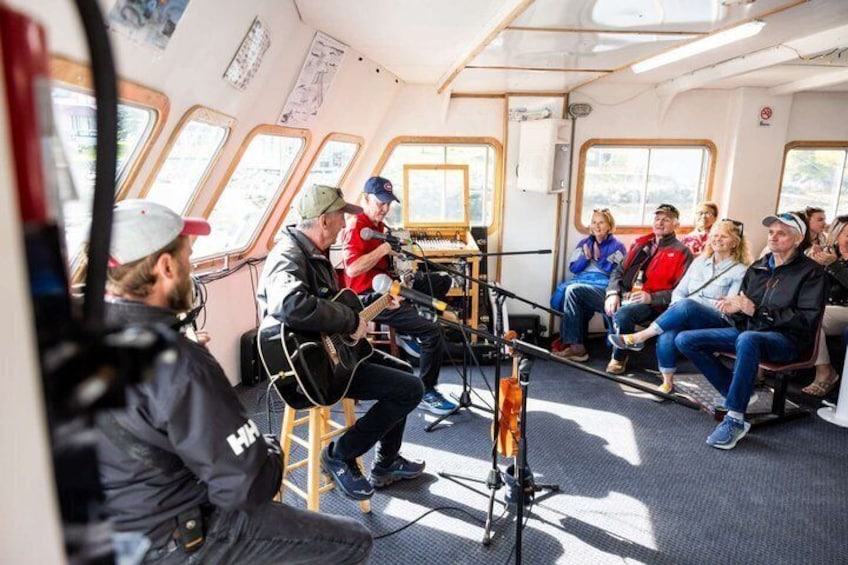 A group of people on a boat with a musician playing a guitar. 5