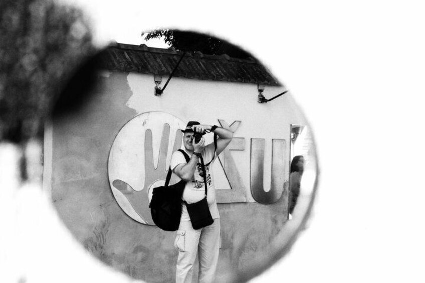 A person taking a photo with a large sign in the background. 2