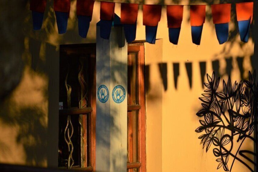 A building entrance with a wooden door, two blue circular signs, and a decorative metal plant. 5